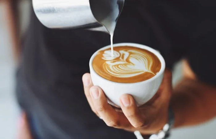 Hand pouring milk into a latte.