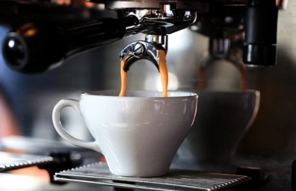 Espresso pouring into white cup.
